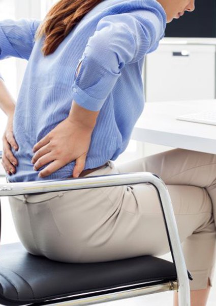 Woman sitting at desk, dealing with back pain